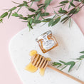 Load image into Gallery viewer, a jar of honey sitting on top of a white plate