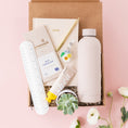 Load image into Gallery viewer, a box of personal care items on a pink background