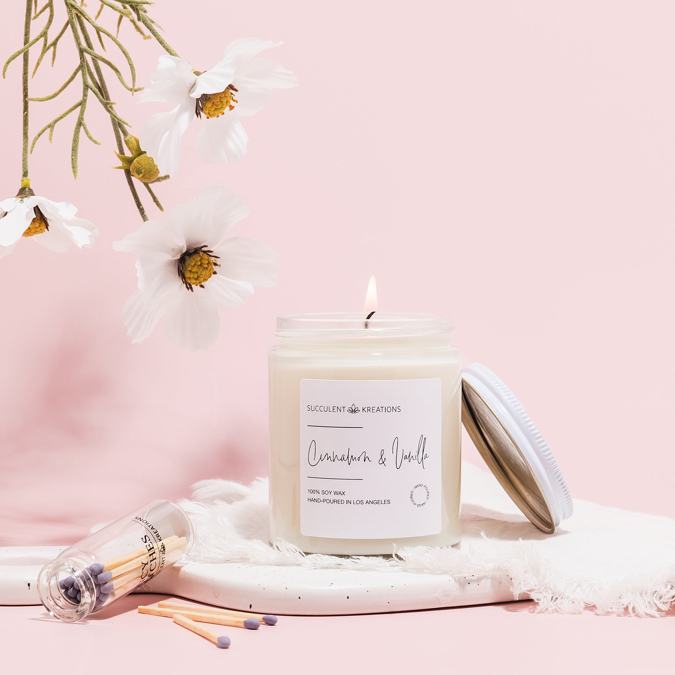 a white candle sitting on top of a white blanket