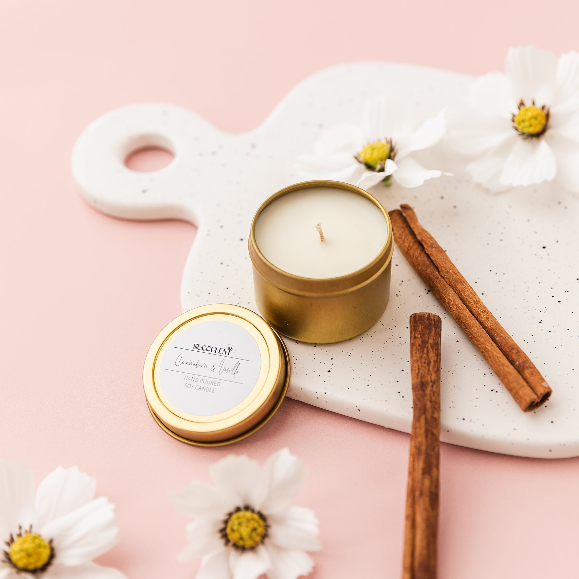 a candle and some cinnamon sticks on a tray