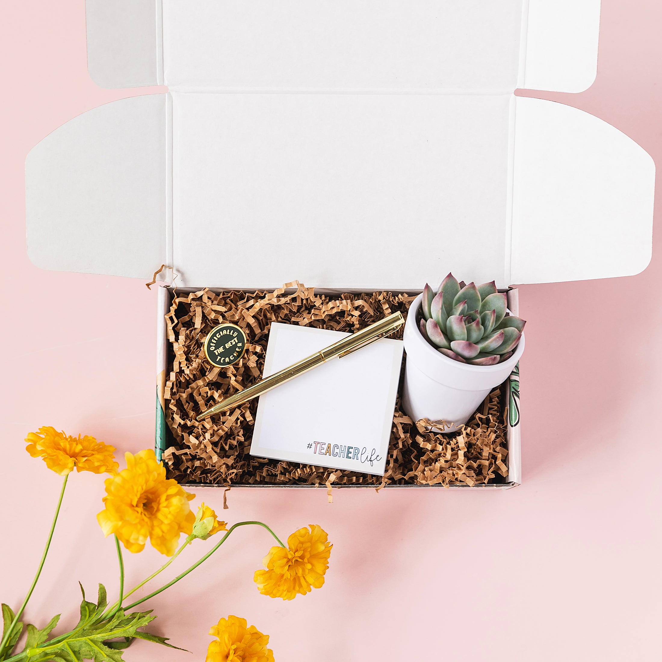a white box containing a notepad, pen, and a potted plant
