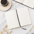 Load image into Gallery viewer, an open notebook sitting on top of a table next to a cup of coffee
