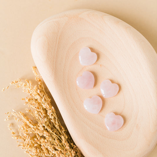a wooden spoon with hearts on it next to a plant