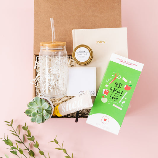 a gift box containing a book, a glass of water, a notepad,
