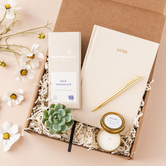a box with a notepad, pen, and a candle