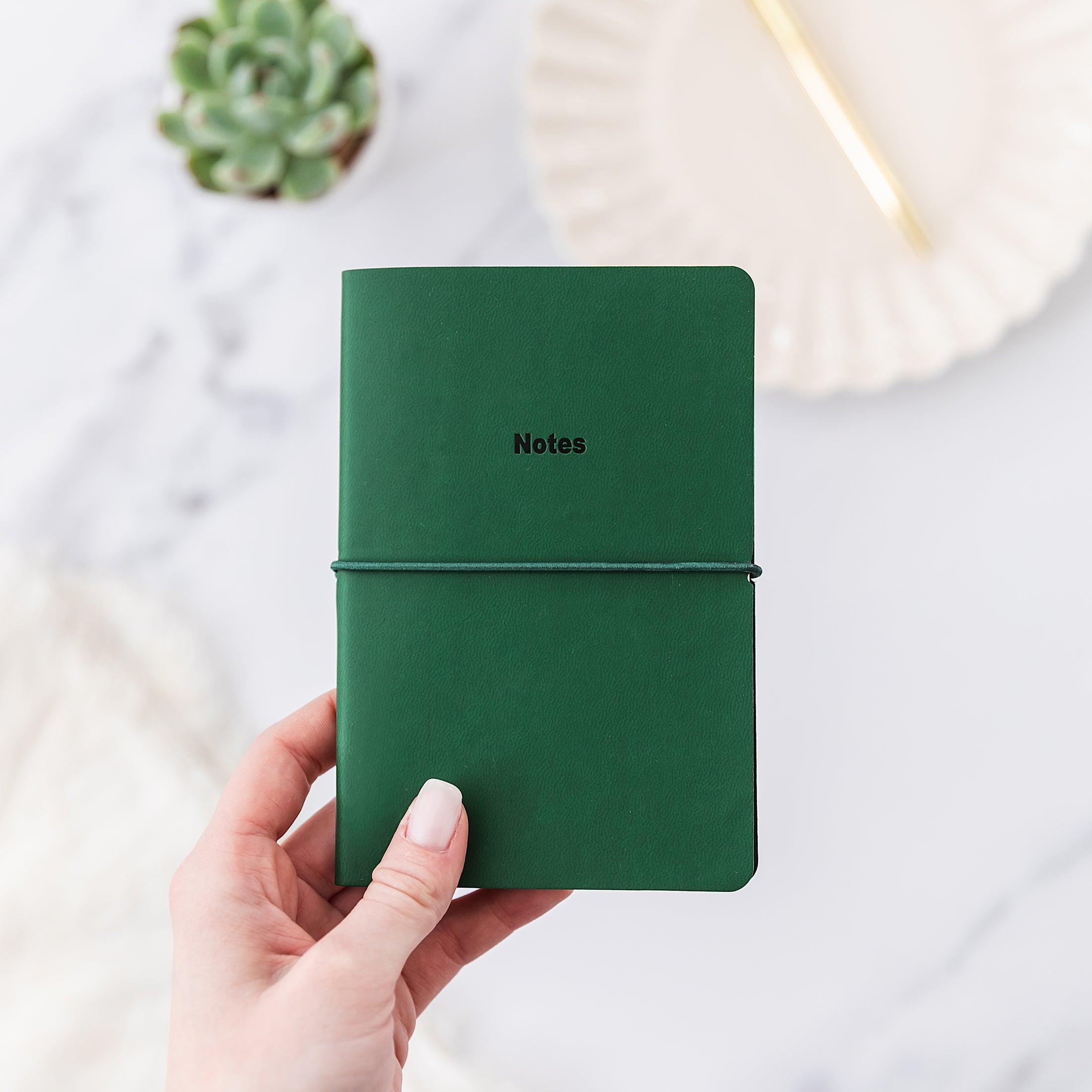 a person holding a green notebook with the word notes written on it