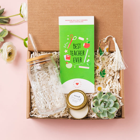 a gift box with a green book, a jar, a candle, and a